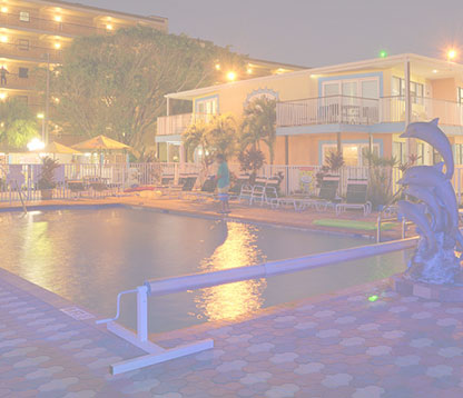 Night view of the Plaza Beach Hotel pool, illuminated by soft lights, with the beachfront resort in the background.